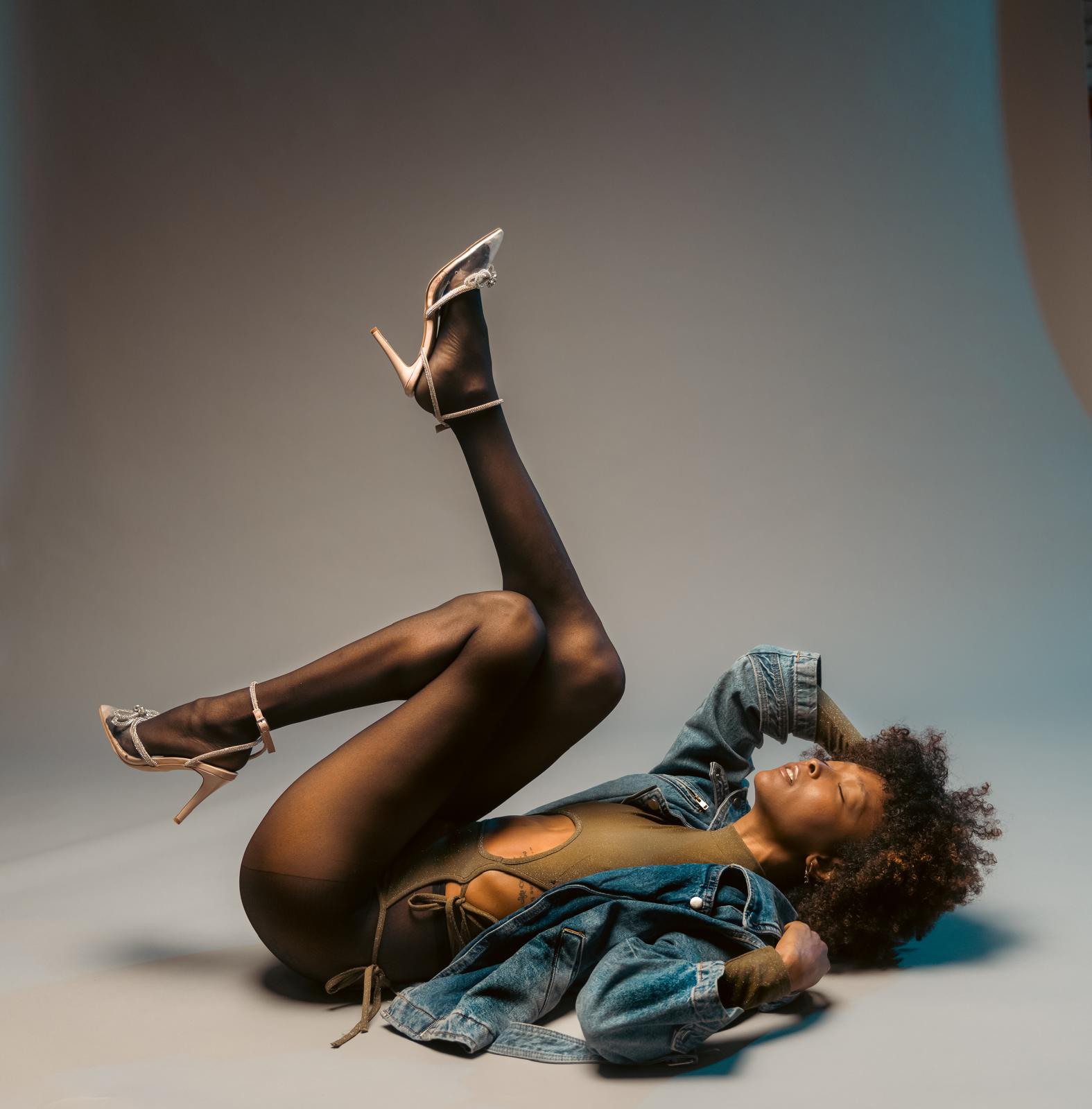 Editorial studio portrait, reclined with knees folded and arms overhead